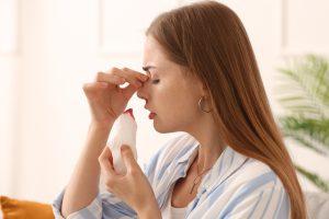 young,woman,with,nosebleed,and,tissue,at,home,,closeup
